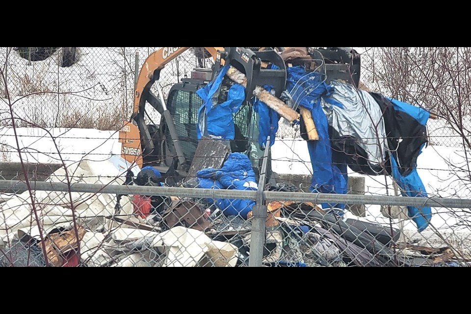 A bobcat operator picks up a load of tarps used at one of the abandoned shelter sites at Moccaasin Flats on Wednesday (Jan. 14 , 2025).