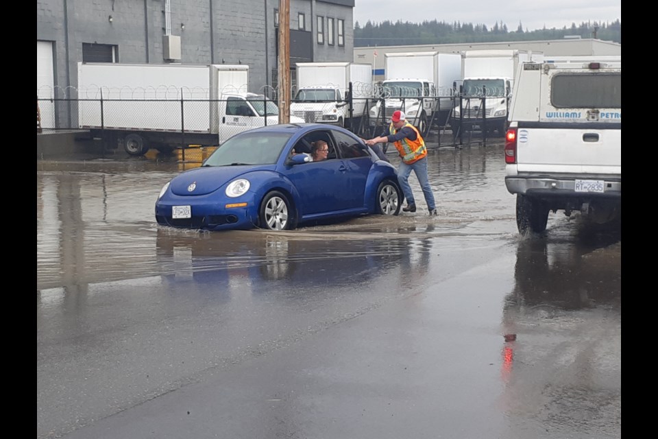 Jason Davis and (hidden behind vehicle) Emerson Muratori get their feet wet pushing Tanya McKaig's car out of a huge puddle. The vehicle stalled when McKaig tried to drive through on Ontario Street between Second and Third Avenues after an afternoon thunderstorm dumped heavy rain on the city Tuesday.