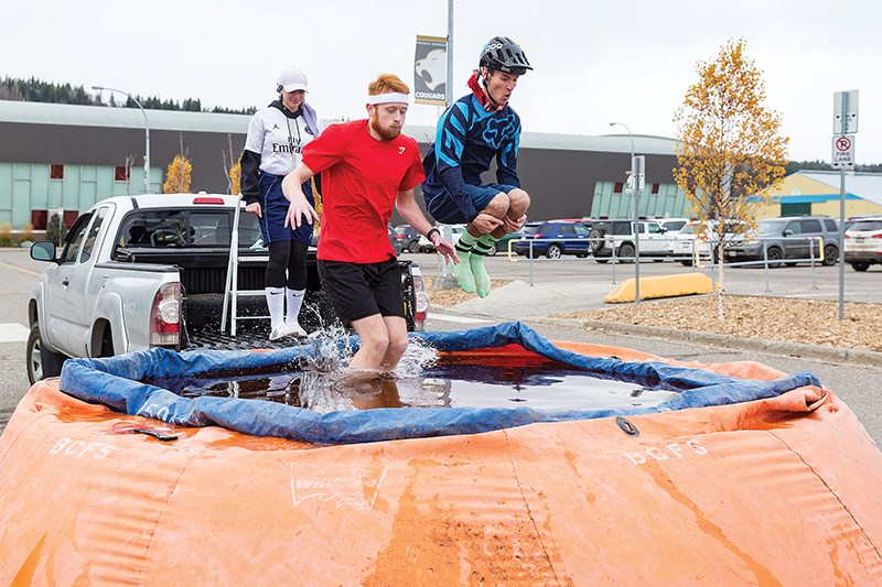 Citizen Photo by James Doyle. Nadia Mansour looks on as Marketing teammates Collin Joyce, left, and Nick Jansa, right, leap into a pool of ice cold water on Saturday afternoon in front of CN Centre during UNBC JDC West's annual Chillin' for Charity fundraiser.