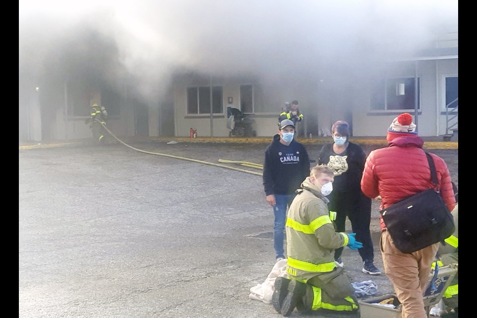 Prince George Fire Rescue firefighters provide first aid to a woman whose motel suite burst into flames Sunday morning at Knights Inn. 
