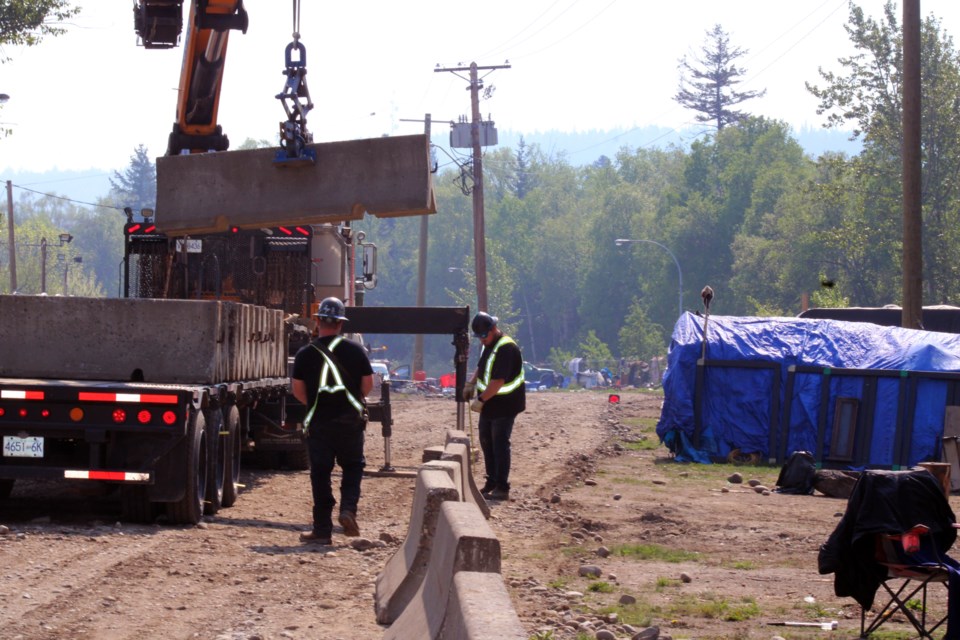 A city crew installs concrete barricades at the Moccasin Flats encampment at Lower Patricia Boulevard on the east side of downtown Prince George.