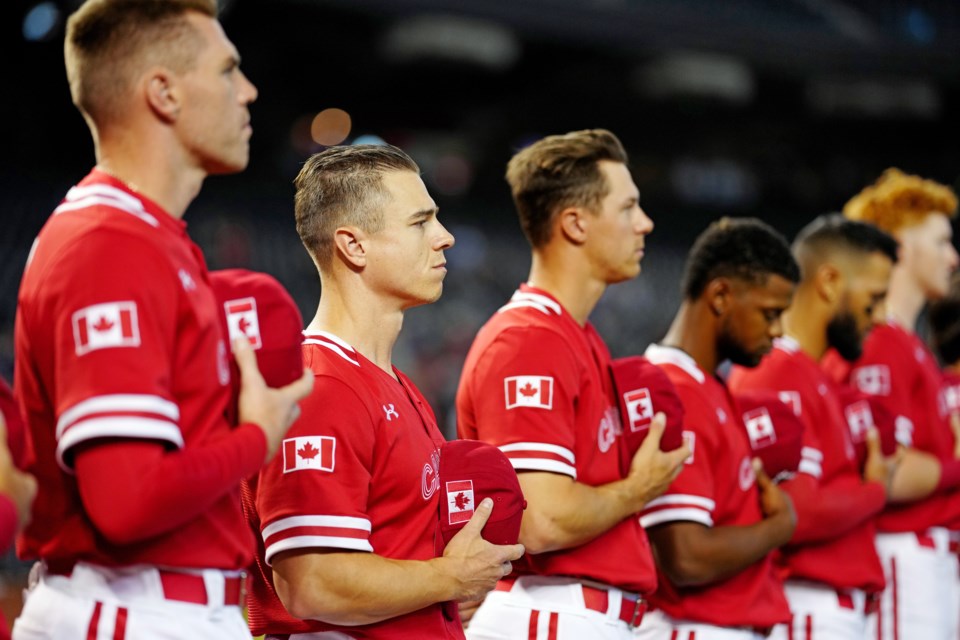 Jared Young of Prince George, third from left, stands next to his Team Canada teammates, Tyler O'Neill, left, and Freddie Freeman, far left, while the national anthems were played prior to their opening game at the World Baseball Classic against Great Britain, March 13, 2023 at Chase Field in Phoenix, Ariz.