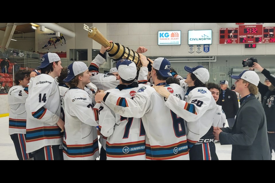 The jubilant Okanagan Rockets gather around the trophy celebrating their 3-2 overtime win over the Cariboo Cougars Sunday, March 23, 2025 at Kin 1. At right is Hudson Getzlaf (No. 20), who fired the winning goal 4:26 into OT.