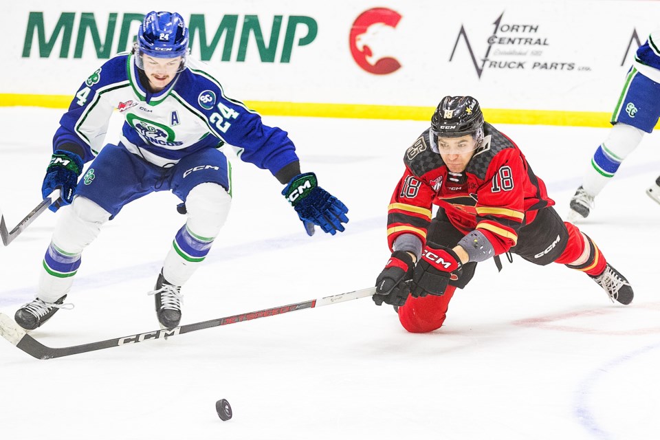 Cougars winger Borya Valis, right, tries to chip the puck away from Swift Current Broncos forward Carlin Dezainde during Tuesday's WHL game at CN Centre/. Dezainde, a former Cougar, scored two goals but it wasn't enough as the Cats beat the Broncos 8-3.