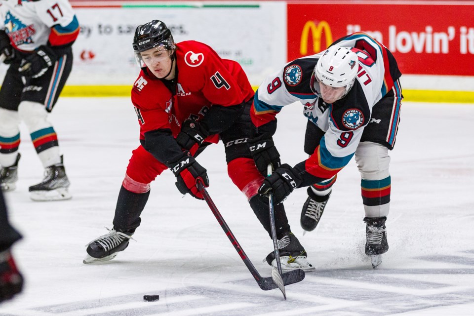 Ethan Samson of the Cougars battles Kelowna Rockets forward Mark Liwiski for puck possession during their game Saturday at CN Centre. The Rockets won 3--2 to sweep the weekend doubleheader.