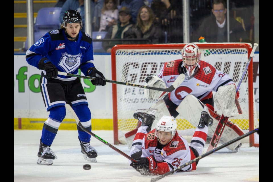 Cougars defenceman Arseni Anisimov falls to the ice in front of goalie Josh Ravensbergen while being watched by Victoria Royals forward Brayden Boehm during Friday's game in Victoria.