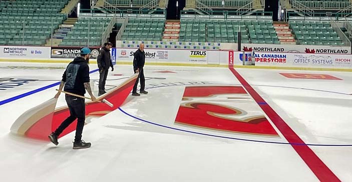 CN Centre maintenance staff members, from left, Duncan Bachand, Onkar Parmar and Terry Baratta apply the Prince George Cougars' logo to centre ice Thursday afternoon. The Cougars start training camp on Aug. 29.