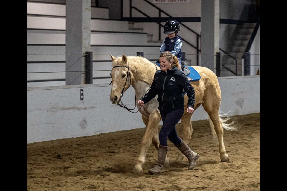 Riding coach Susie Palley keeps pace with her grandson Everett Kohlen, 4, as he rides Jake around the Agriplex.