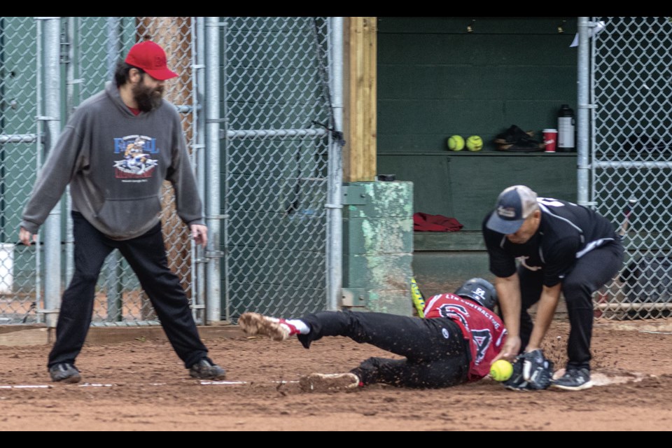 Big Guy Lake No. 64 tries to dive back to third base where the Custom Edge third baseman tries to get the tag out in their Friday night game at the Kyle Garnot Memorial Fastpitch Tournament.