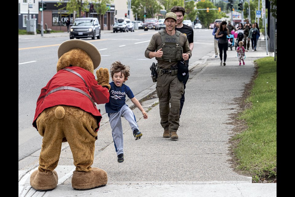 James Brasse, 4, leaps up for a high-five from Safety Bear as he leads his father, RCMP officer Alex Brasse, across the finish line at the Law Enforcement Torch Run Thursday, June 6, 2024 in Prince George, B.C. 