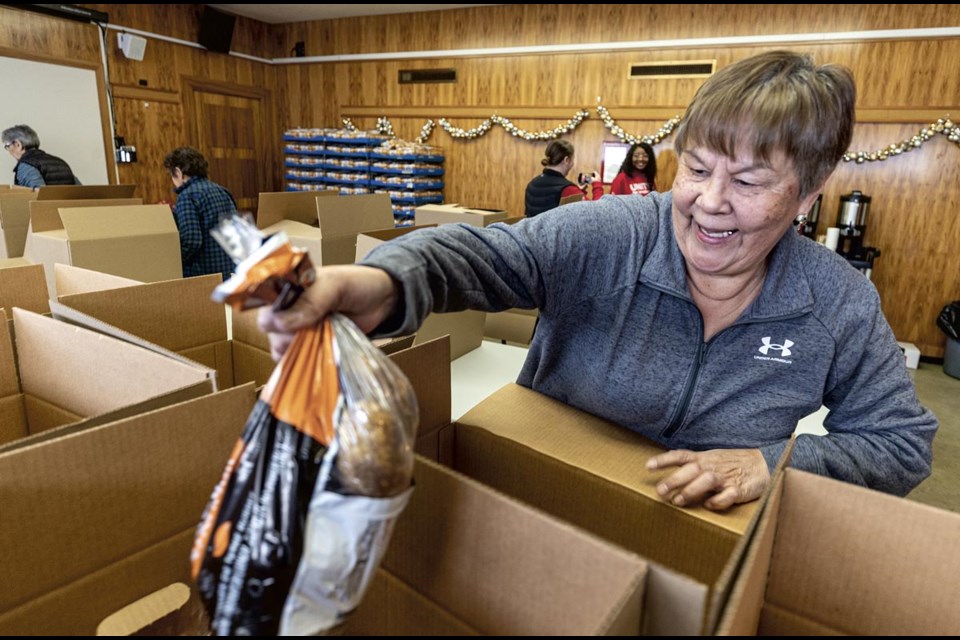 Elder Pearl Lalond drops bags of potatoes into hampers at the Native Friendship Centre Wednesday.