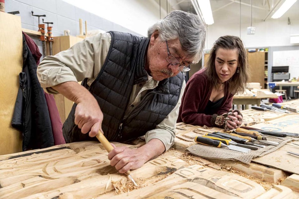 Peter George works on refurbishing a School District 57 sign he originally carved 20 years ago, as his daughter and apprentice Hailey watches how he strips away dry and cracked wood while working in the  woodworking shop at the Alternative Learning Centre in Prince George.