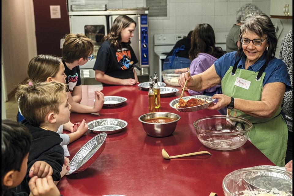 Anna Monetta shows the kids how much sauce to use and how to apply it once they got their dough worked to the correct thickness in the pan during a pizza making class at the Prince George Italian Club on Pro-D Day Monday, Jan. 27.