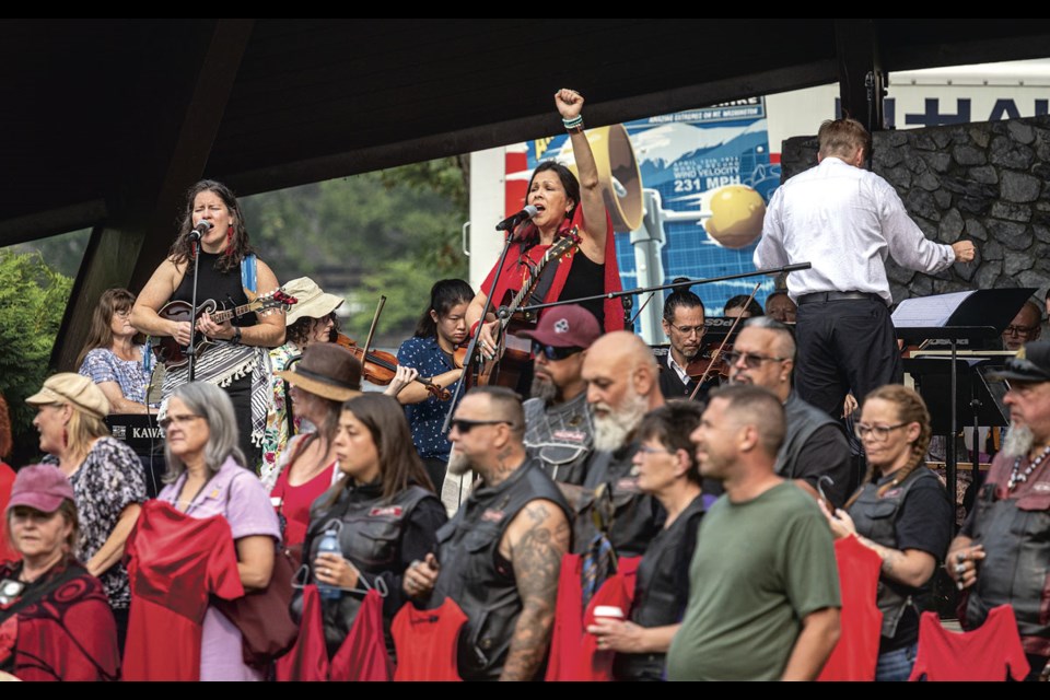 Amy Blanding (left) and Kym Gouchie join the PGSO along with members of the Red Dress Society, the Khast'an Drummers, the Redrum Motorcycle Club at Pops in the Park at the Lheidli T'enneh Memorial Park bandshell.