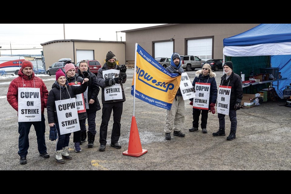 Striking CUPW members react to honks from passing motorists as they walk the picket line at the 15th Avenue postal facility Friday morning.