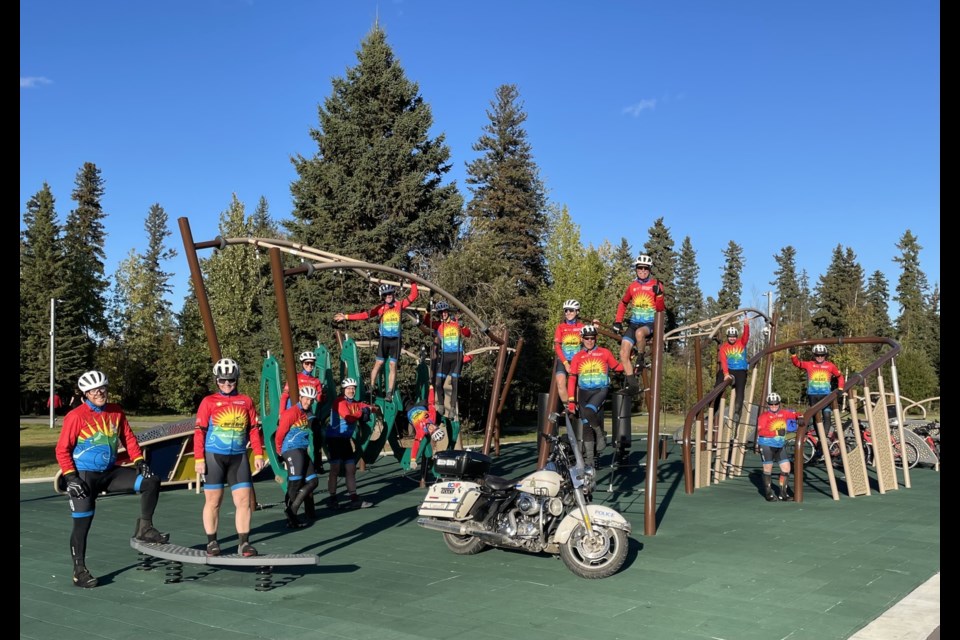 A group of riders gather for a photo on a playground. 