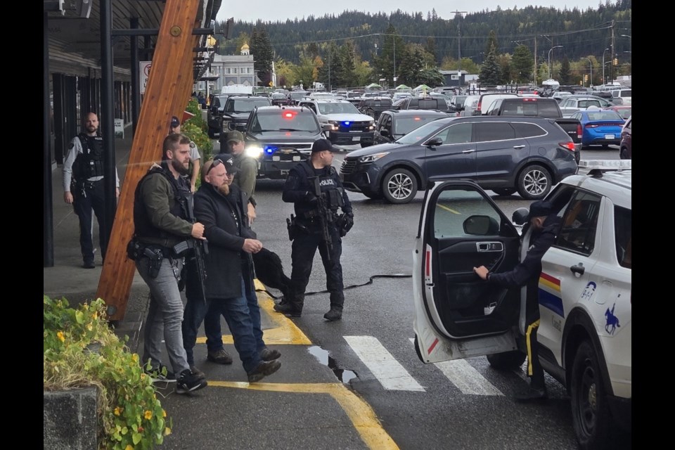 A man is led out of the CIBC branch at Spruceland Mall on Wednesday, Oct. 2, 2024 in Prince George, BC. RCMP maintained a heavy presence at the plaza after an incident around the noon hour.