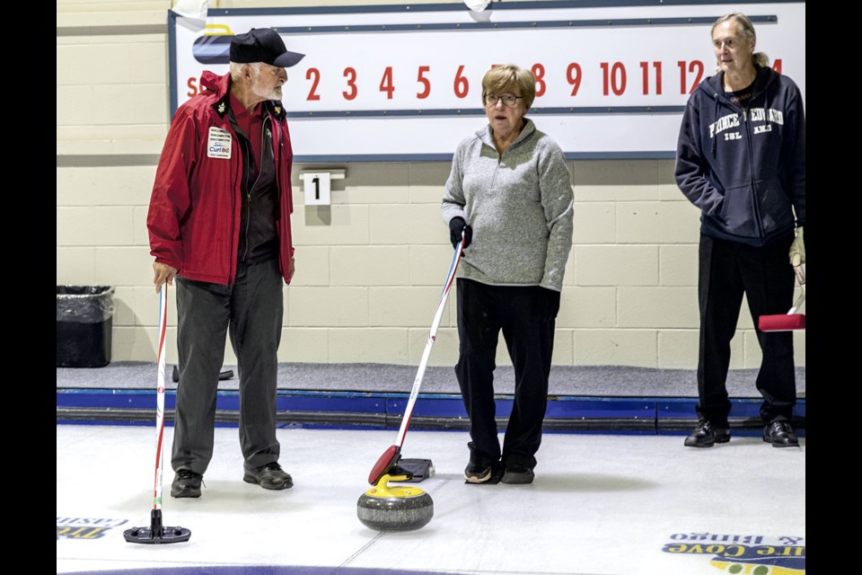 Ruth Meger gets instruction on sturling, or stick curling, from Gary Sheransky while husband Clair watches as they attend a Sturling open house at PGG&CC Saturday.