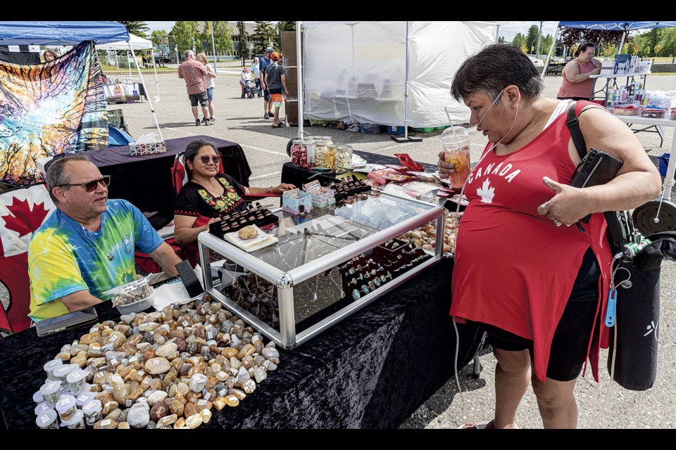 Denise Lowley discusses the jewelry made by Russell and Edita Crick at their booth in the CN Centre parking lot for the Sweet Summer Market Saturday. The market ran from 10am to 5pm with local vendors and artisans along with food trucks in attendance.