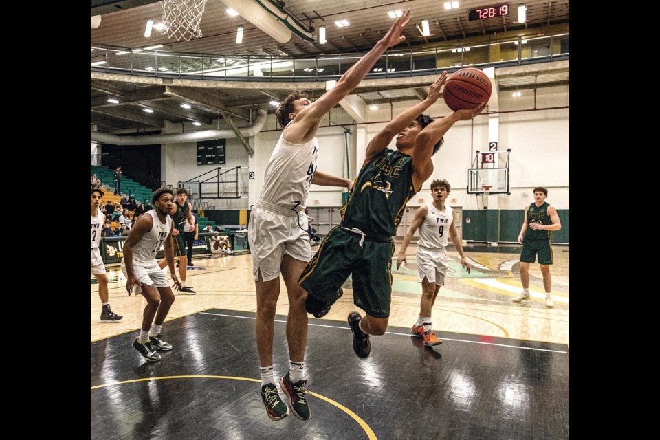 Timberwolf Isaiah Bias twists in the air to avoid the block of Spartan Caleb Gremaud Saturday at UNBC's Brownridge Court.