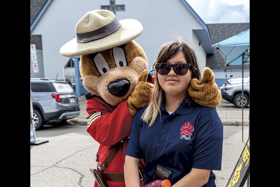 Myla West, 13, poses for pictures with Safety Bear as she enjoys an afternoon at a block party held to celebrate the 10th anniversary of the detachment building at Fifth Avenue and Victoria Street Saturday afternoon.