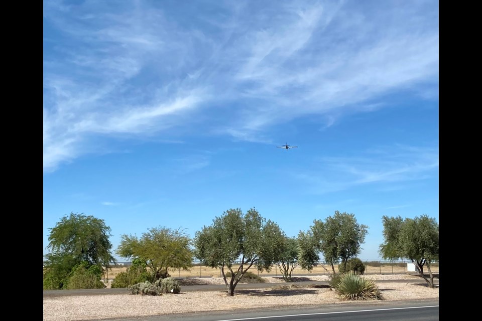 An airplane flies over the South Ellsworth Loop Road in Queen Creek for a landing at Chandler Municipal Airport.