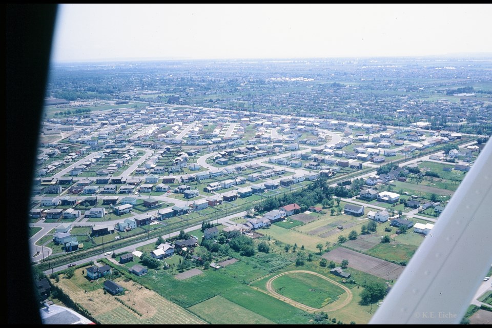 Aerial view looking south-east, 1968, over the subdivision known officially as Richmond Gardens and informally as Brighouse Estates, begun in the early 1960s by the Consolidated Building Corporation. No. 2 Road, the western boundary of the subdivision, can be seen from lower left to upper right, with two cars travelling on it; Granville Avenue, the southern boundary of the subdivision, is visible in the upper part of the view.