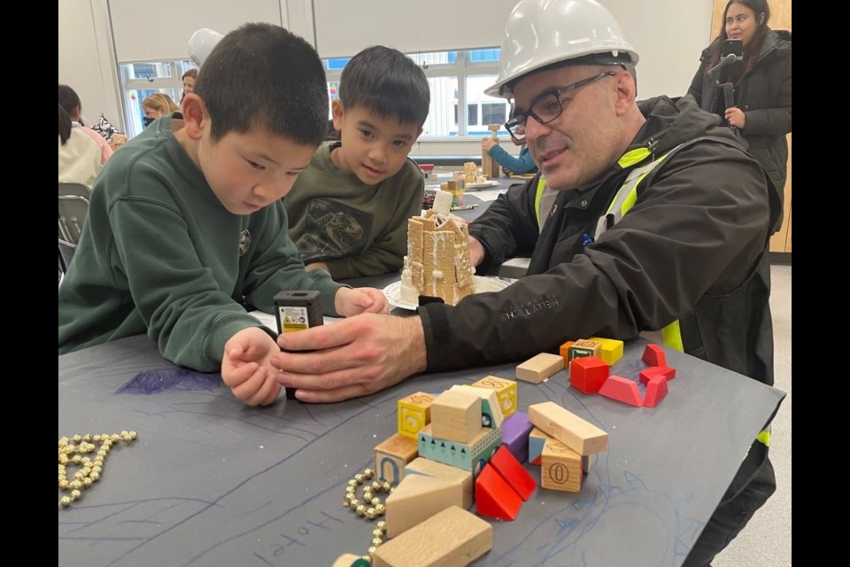 Justin Wagner, a City of Richmond building inspector checks how well Manoah Steves elementary students had built their gingerbread houses.