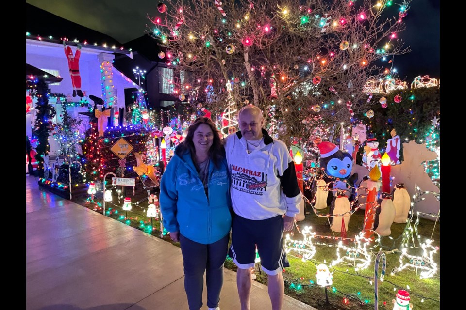 Ken Glasspool and his wife Cindy in front of their front yard packed with Christmas decorations and lights.