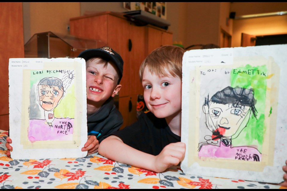 Banff Elementary School Grade 2 students Charlie Gagnon, left and Emmett Kaufmann pose with Banff resident Lori Dowling's portrait during the intergenerational portraits event in the Pioneer Room in the Catharine Robb Whyte Building in Banff on Friday (June 7). JUNGMIN HAM RMO PHOTO 