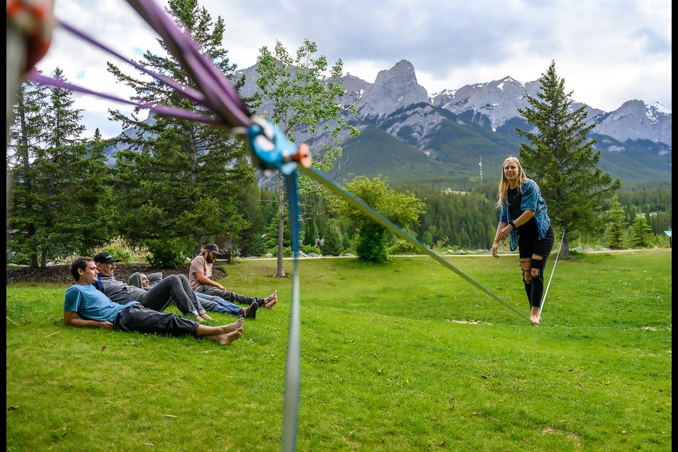 Hannah Lightfoot talks with her friends while walking a slackline in Canmore at Riverside Park on Monday (June 24). The slackliners host jam nights every Monday at the park for people to try walking the lines or to hang out. MATTHEW THOMPSON RMO PHOTO