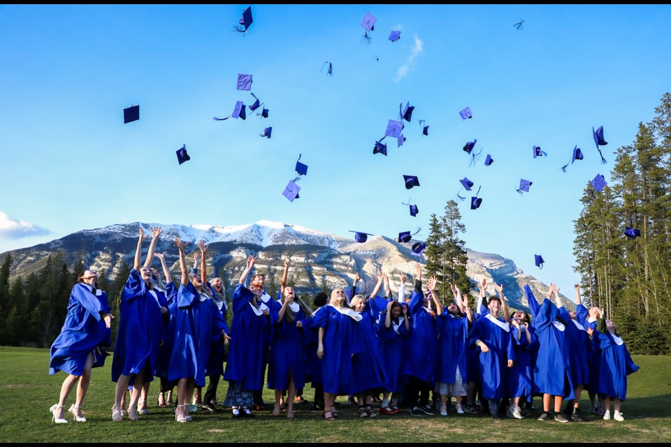 Graduates from Our Lady of the Snows Catholic Academy toss their mortarboards in the air at the school field in Canmore on Thursday (May 30). JUNGMIN HAM RMO PHOTO