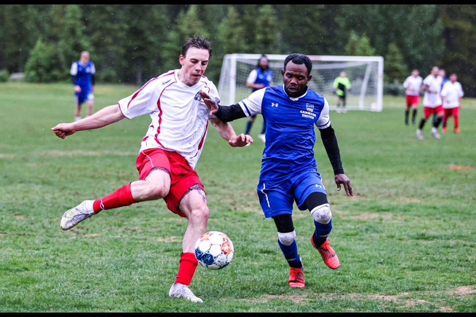 Rundle FC's Charlie Heisz, left, and Canmore United's Gary Hinds fight for the ball during a match in the Bow Valley Soccer League at Our Lady of the Snows Catholic Academy Field in Canmore on a rainy Thursday (June 27). The game ended in a 4-4 tie.    JUNGMIN HAM RMO PHOTO 