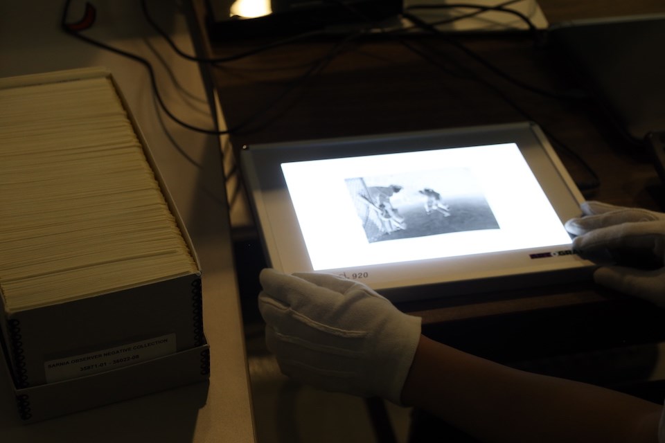 A photographic negative of people playing hockey is put on a lightbox at Lambton County Archives..JPG