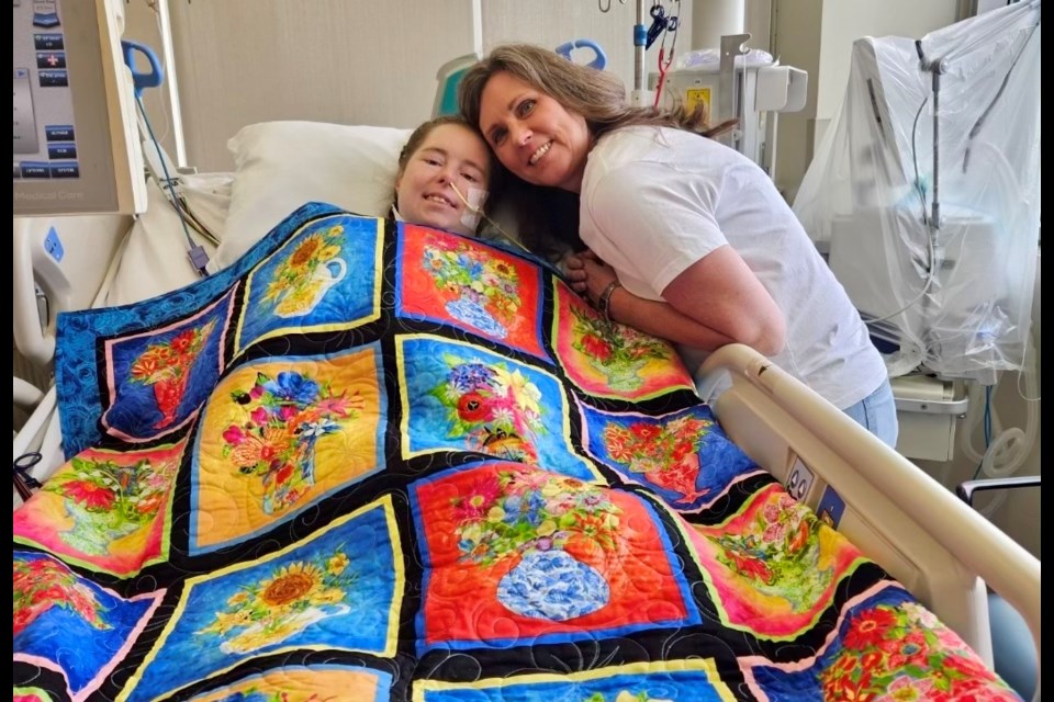 Helen Van Sligtenhorst with her daughter Sydney in University Hospital's ICU nearly a month after Sydney's heart transplant. The quilt was a gift from the Brigden Quilters Guild.