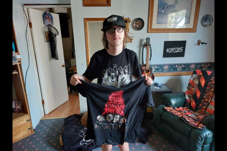 Alex with just one of the 150+ t-shirts that he's collected over the years at live music shows. Photo by Derek Ruttle.