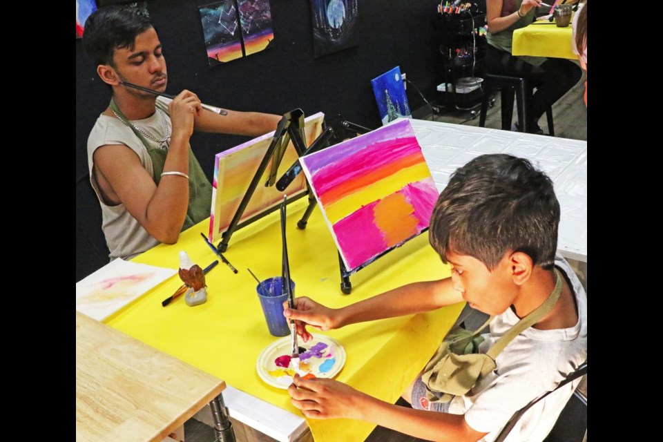 Anubhav Sharma, left, and Aarav Sharma worked on their paintings of a sunset, during a paint night at the Collabartive Studio on Wednesday evening.