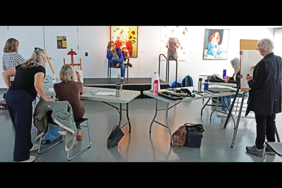 Artist Iris Hauser, at left, talks with one of her students in a live-model portraiture class on Saturday, with sculptor Christiane Stollofen as the model.