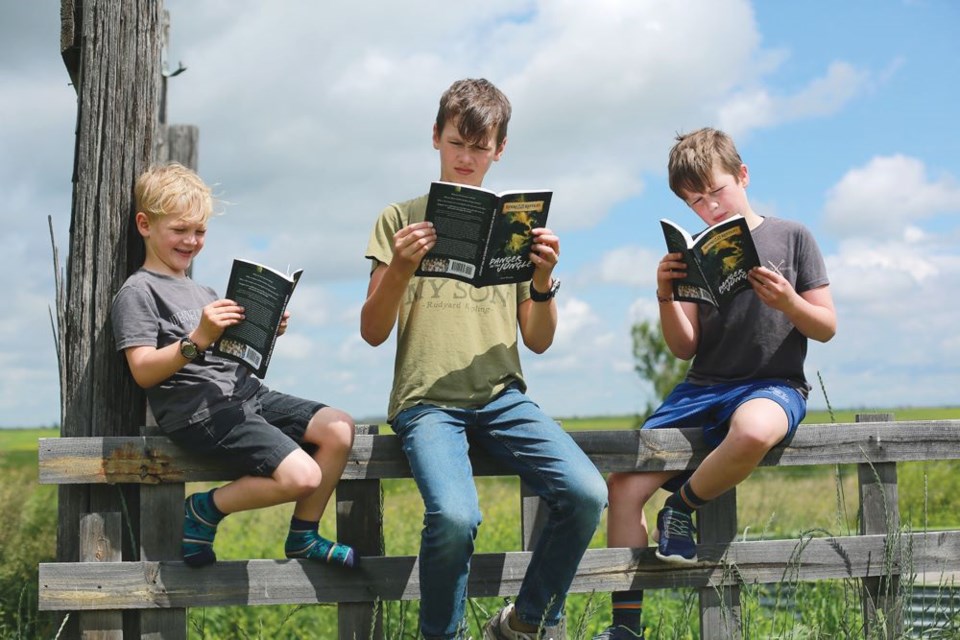 Five-year-old Arrow, Sterling (12), and Justice (10) Weening enjoy reading their father's first novel. Photo courtesy of Jason Greening