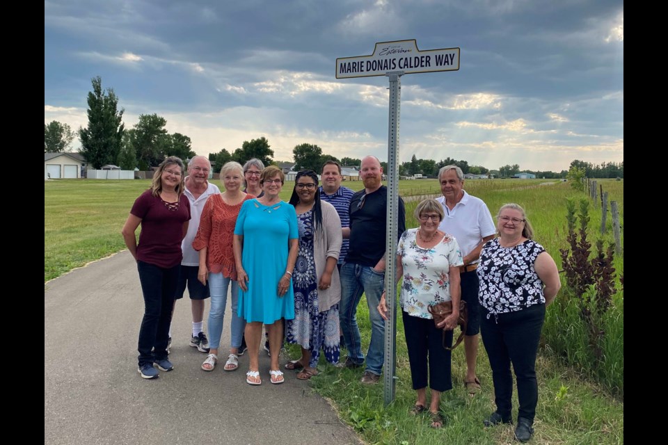 Marie Donais Calder, middle, her family and friends gathered by the new sign at pathways on July 6. 