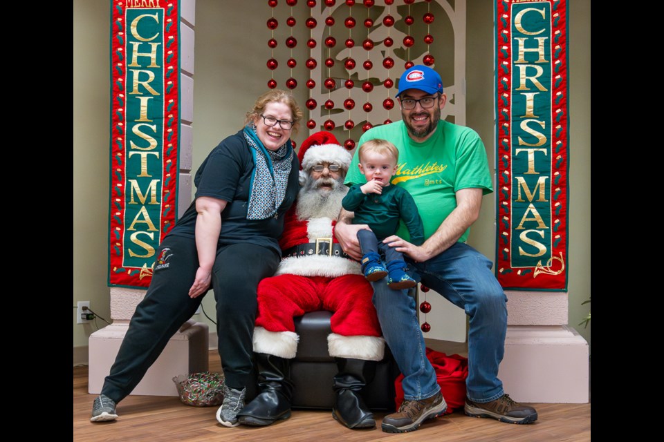 Emily, Sam and Jeff have their pictures taken with Santa.