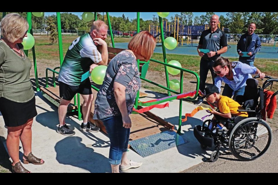 From left are principal Arlene Dobson, v-p Tyson O’Dell, teacher Tanice Abramson, Kim Neithercut assisting student Caiden Hahn to break the ribbon, and in the background - Dustin Bell of Souris Valley Industries, and Brandon Rosengren of Access.