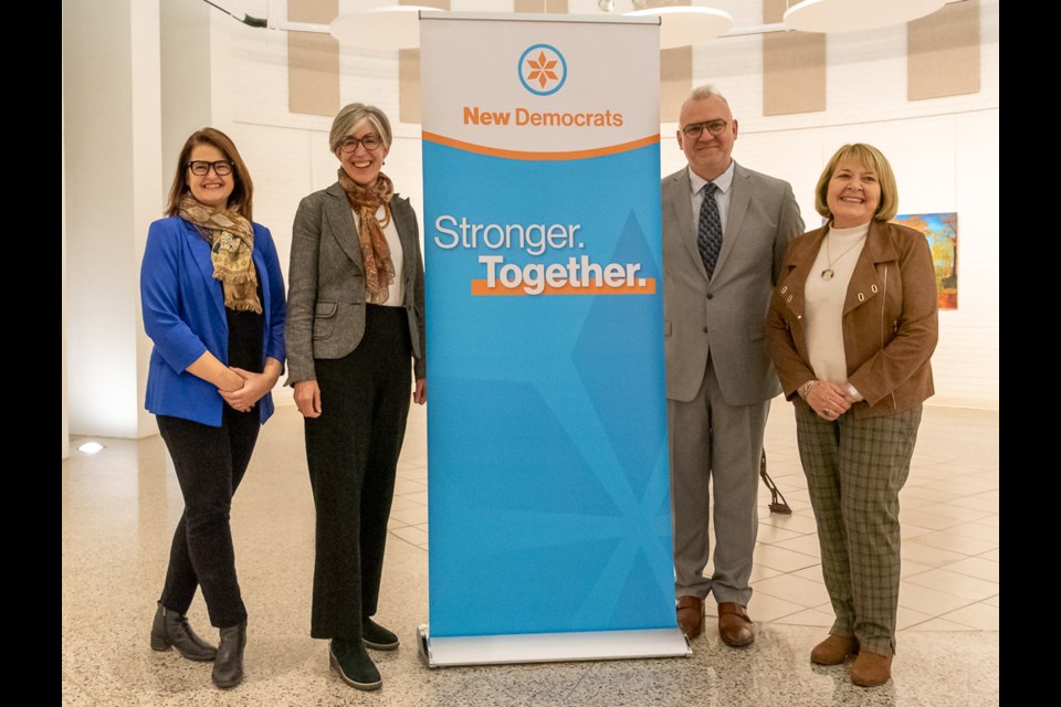 Carla Beck, Leader of the New Democrats of Saskatchewan, Erica Ritchie MLA for Saskatoon Nutana and Tom's cousin, Tom Kroczyński, Battlefords NDP and Judy Bradley, President of the Saskatchewan NDP pose for a photo by the NDP banner