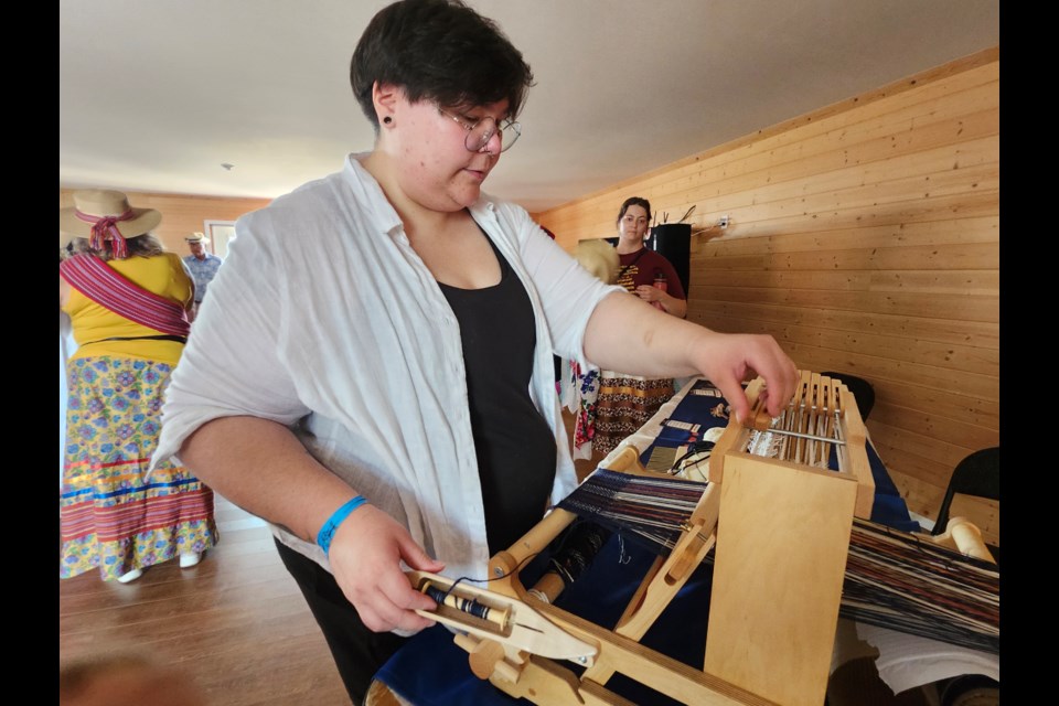 Gabriel Marchand demonstrates how to make a sash using a loom in the Métis Nation of Alberta delegation's pavilion at Back to Batoche 2024. 