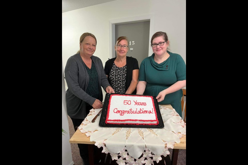 Shelly Gerein, Mary Nestmann and Amanda Roth ready to serve the 50th anniversary cake to those who attended the milestone celebration for Wilkie Housing Authority Aug. 9.