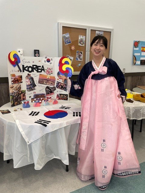 A staff from BTEC stands beside the Korea poster during the Taste of Culture Week at BTEC.