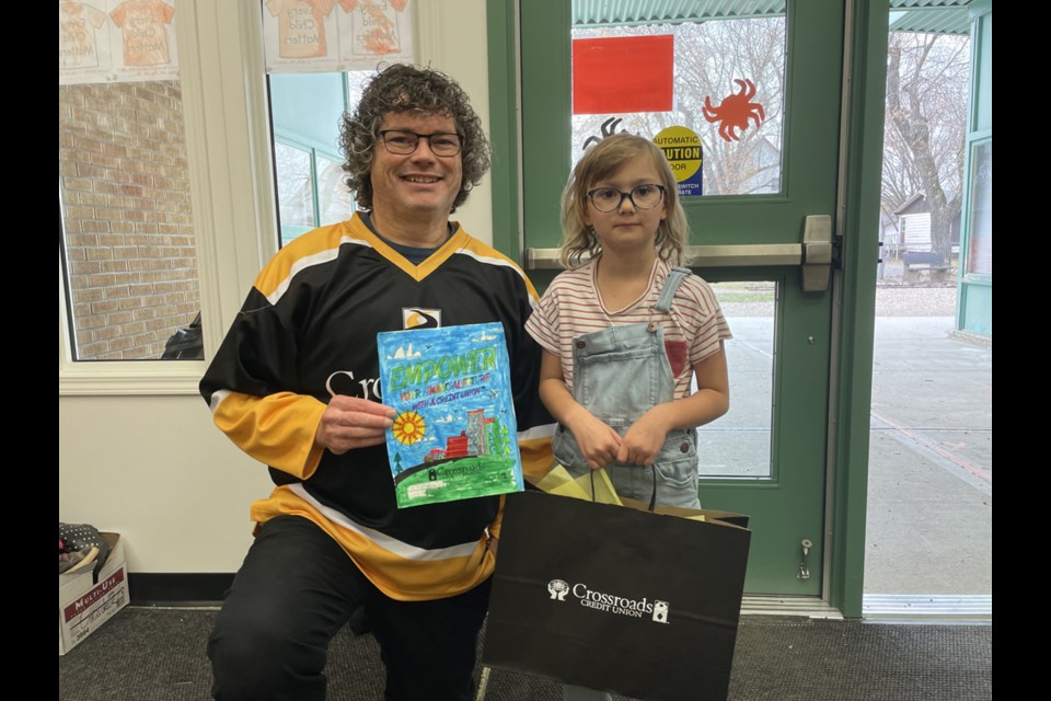 Jett Olynyk, Grade 1 student, seen here with Crossroads staff member Sean Plosz, was the Canora Junior Elementary School winner of the Credit Union Day colouring contest. Each winner won an individual prize package and the choice between a pizza party or $150 worth of books for their classroom.