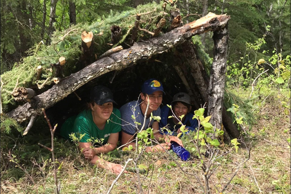 An example of land-based learning utilized in the division as students from Spiritwood High School at a camp at Ness Creek work with knowledge keeper Evan Chamakese to learn protocols and tips for survival shelters.