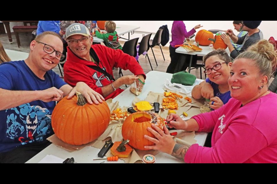 Justin and Gerald, at left, and Robin and Chantal at right, from Weyburn Group Homes, worked on pumpkins at the carving session at the Weyburn library on Thursday evening.