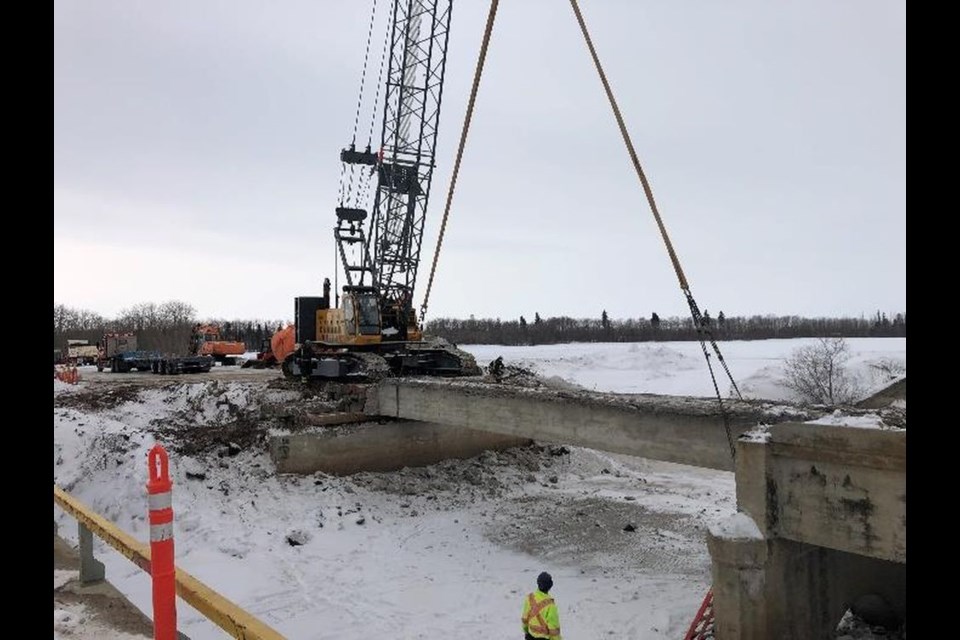 A new bridge is under construction over the Assiniboine River on Hwy No. 9 north of Canora. In this photo the contractor, Minty’s Moving, is removing the remaining south span concrete girder with a crane.
